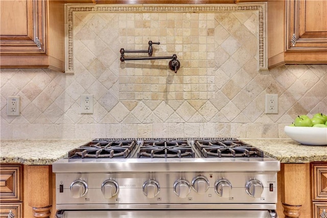 kitchen featuring light stone counters, brown cabinets, backsplash, and high end stove