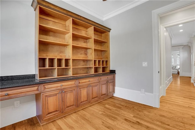unfurnished office featuring light wood finished floors, built in study area, baseboards, and ornamental molding