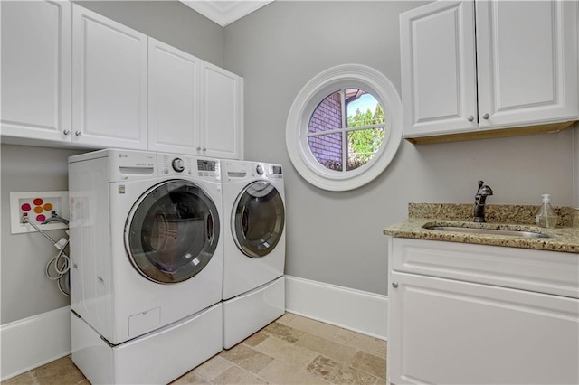laundry room with independent washer and dryer, stone finish floor, a sink, cabinet space, and baseboards