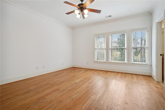 spare room with visible vents, baseboards, light wood finished floors, ceiling fan, and ornamental molding