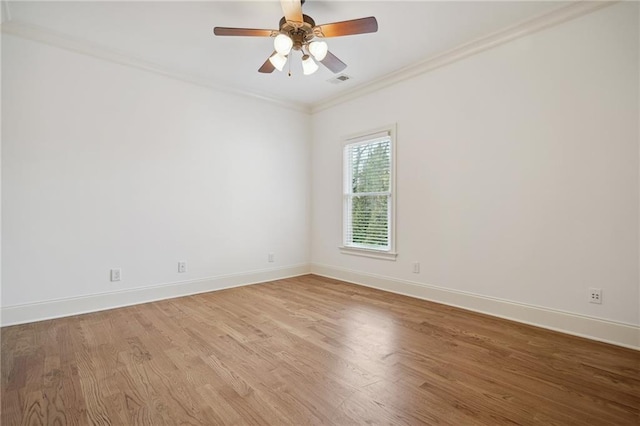 unfurnished room featuring visible vents, wood finished floors, baseboards, and ornamental molding