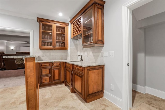 bar featuring decorative backsplash, wet bar, baseboards, and a sink