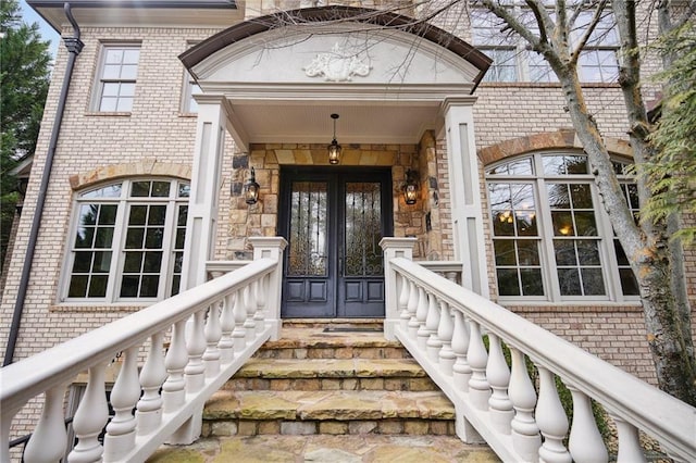 doorway to property featuring french doors, stone siding, and brick siding