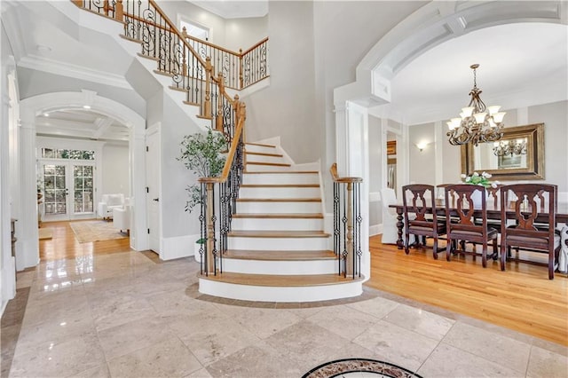stairway featuring arched walkways, ornamental molding, and a towering ceiling