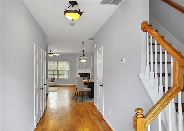 hallway featuring stairs, visible vents, and wood finished floors