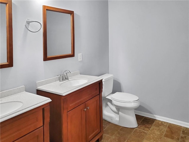 1649 Southgate Mill Dr, Duluth, GA 30096 - bathroom with stone tile floors, toilet, two vanities, and baseboards