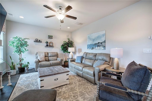 living room with visible vents, baseboards, wood finished floors, and a ceiling fan