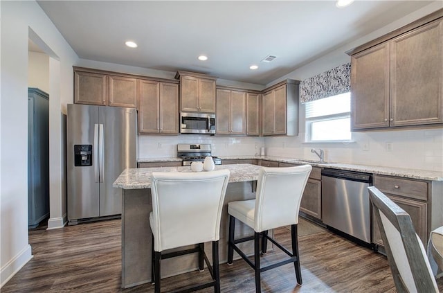 kitchen featuring backsplash, appliances with stainless steel finishes, dark wood finished floors, and a center island