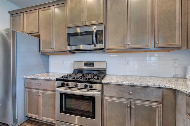 kitchen with light stone counters, stainless steel appliances, and tasteful backsplash