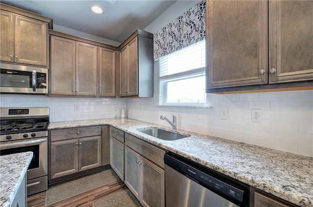 kitchen featuring dark wood-type flooring, tasteful backsplash, appliances with stainless steel finishes, and a sink