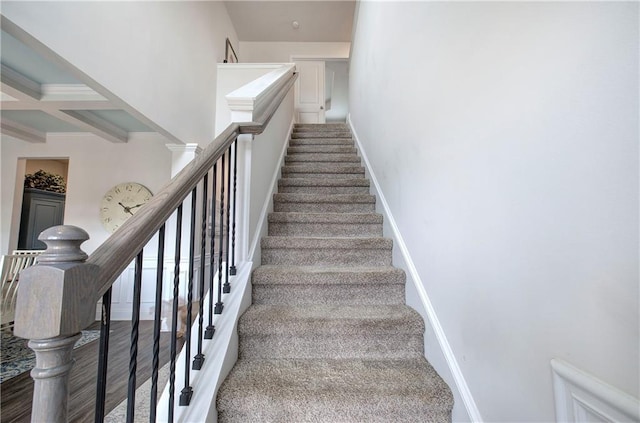 staircase with beam ceiling, coffered ceiling, baseboards, and wood finished floors