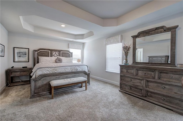 bedroom featuring a raised ceiling, baseboards, and light carpet