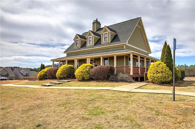 view of front of house featuring board and batten siding, a front yard, covered porch, and a chimney