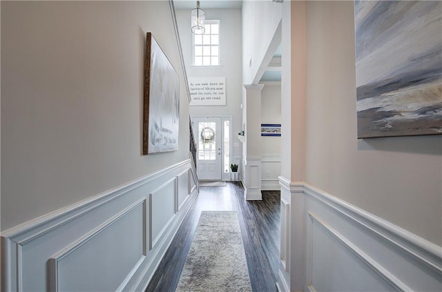 interior space featuring decorative columns, a wainscoted wall, and a wealth of natural light