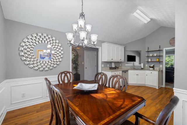 dining space featuring lofted ceiling, hardwood / wood-style floors, sink, and a notable chandelier