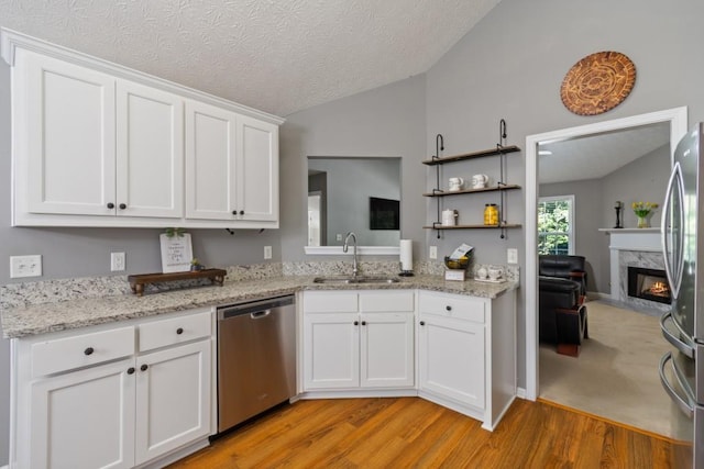 kitchen featuring sink, vaulted ceiling, stainless steel appliances, and white cabinetry