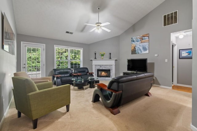 living room with light colored carpet, ceiling fan, high vaulted ceiling, and a high end fireplace