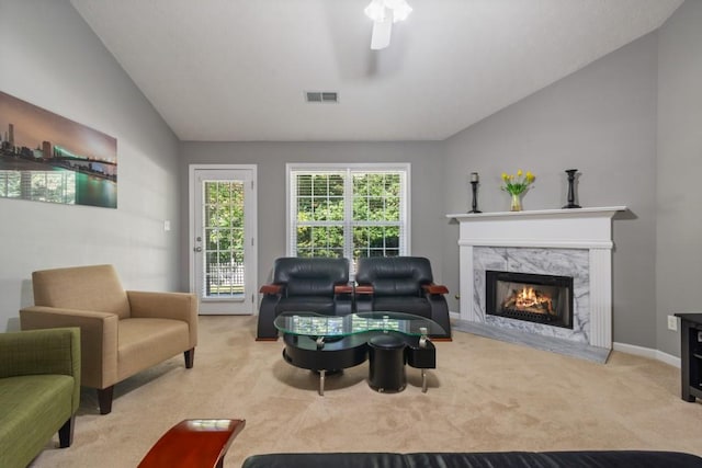 living room featuring light colored carpet, ceiling fan, vaulted ceiling, and a fireplace