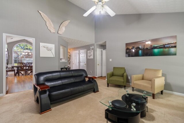 living room with light carpet, high vaulted ceiling, and ceiling fan with notable chandelier