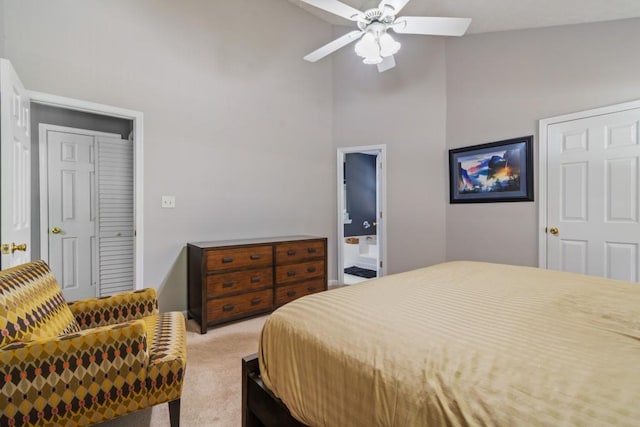 carpeted bedroom with ensuite bath, high vaulted ceiling, and ceiling fan