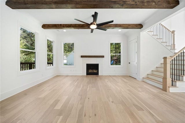 unfurnished living room with beamed ceiling, ceiling fan, and light hardwood / wood-style flooring