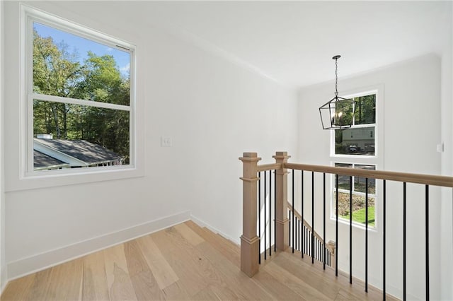 hall with an inviting chandelier, plenty of natural light, and light hardwood / wood-style floors