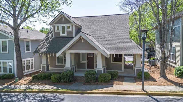 view of front of house with a porch, cooling unit, and roof with shingles