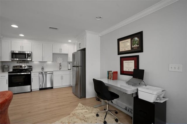 kitchen featuring visible vents, crown molding, white cabinets, a sink, and stainless steel appliances