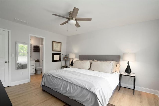 bedroom with baseboards, ceiling fan, wood finished floors, and ensuite bathroom