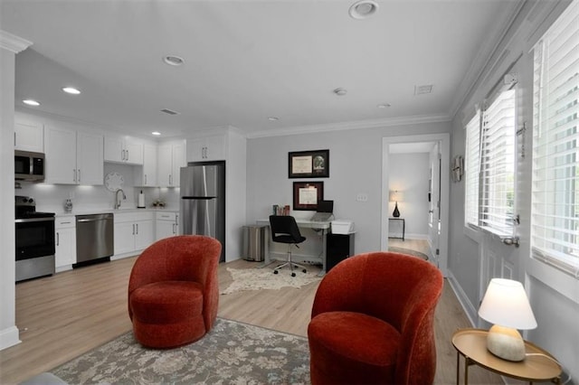 living room with crown molding, a wealth of natural light, and light wood-style flooring