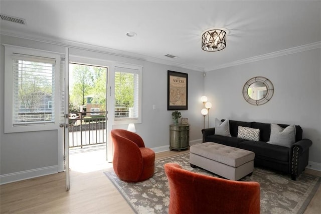 living room with visible vents, baseboards, crown molding, and wood finished floors