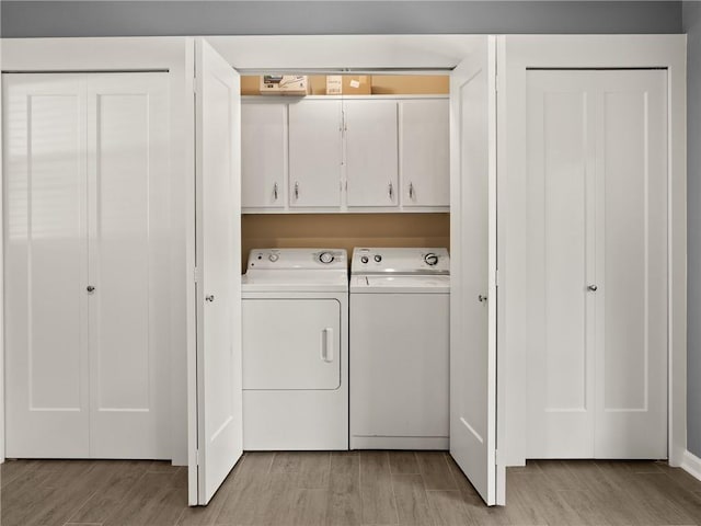 washroom featuring washer and dryer, cabinet space, and light wood finished floors