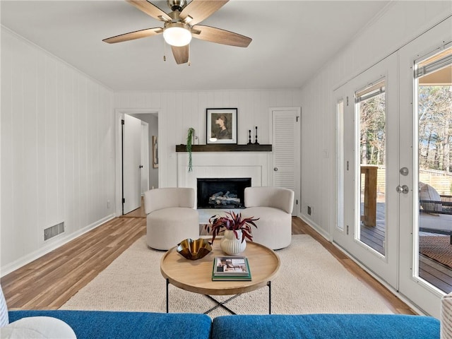 living room with visible vents, baseboards, french doors, a fireplace, and wood finished floors