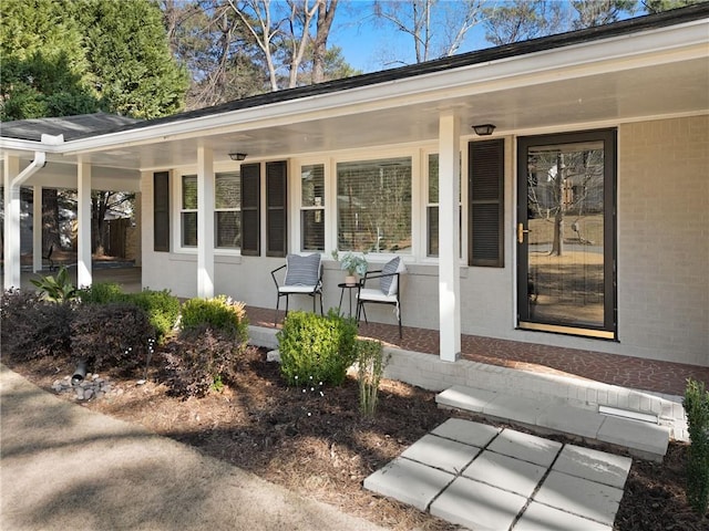 entrance to property featuring brick siding and covered porch