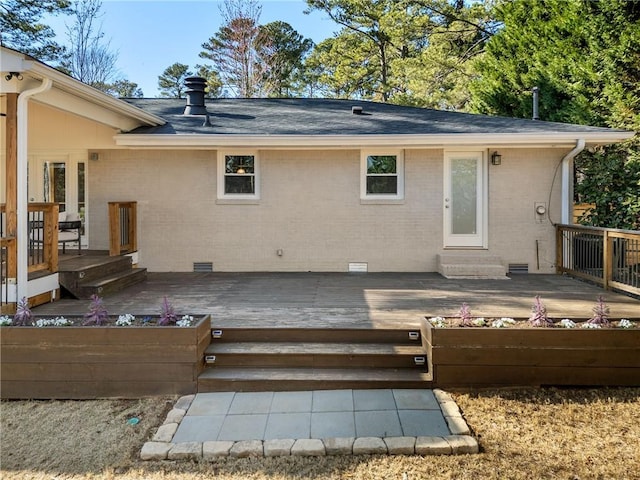 rear view of property featuring crawl space, brick siding, a deck, and a shingled roof