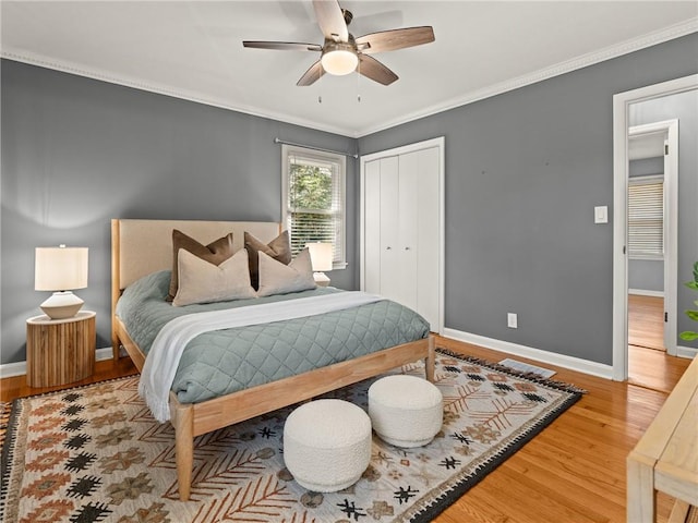 bedroom featuring wood finished floors, baseboards, a closet, and ornamental molding