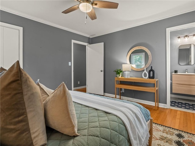 bedroom with ceiling fan, baseboards, ornamental molding, ensuite bathroom, and wood finished floors