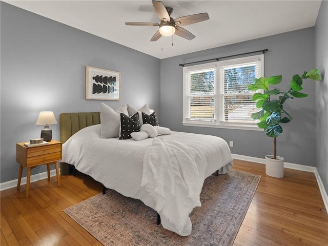 bedroom with ceiling fan, baseboards, and hardwood / wood-style flooring