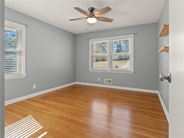 spare room with light wood finished floors, visible vents, ceiling fan, and baseboards