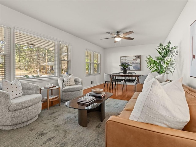 living area featuring wood finished floors, baseboards, and ceiling fan