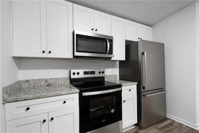 68 Wagon Trail Cir, Dallas, GA 30132 - kitchen featuring appliances with stainless steel finishes, dark wood finished floors, white cabinets, light stone counters, and a textured ceiling