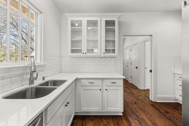 kitchen featuring dark wood-style flooring, backsplash, glass insert cabinets, white cabinetry, and a sink