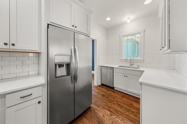 kitchen featuring stainless steel appliances, dark wood-type flooring, a sink, and white cabinets