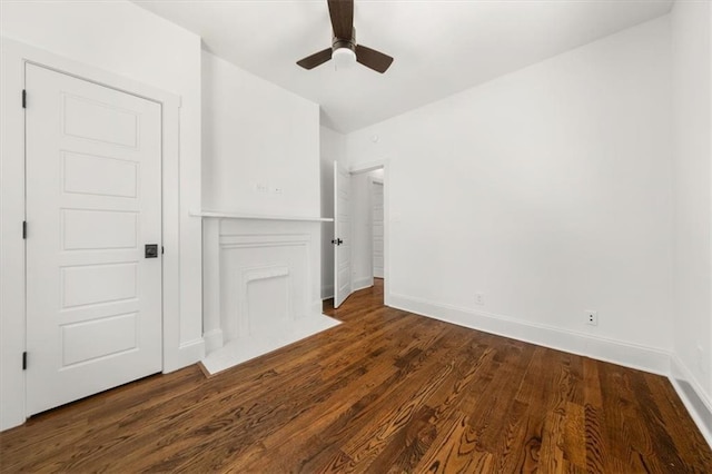 unfurnished bedroom with dark wood-style flooring, a ceiling fan, and baseboards