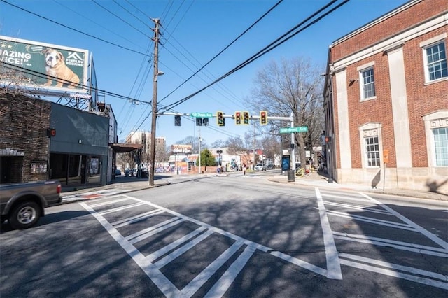 view of road with traffic lights, traffic signs, curbs, and sidewalks