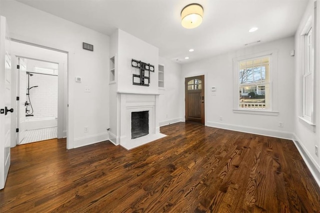 unfurnished living room with dark wood-style floors, a fireplace with flush hearth, baseboards, and recessed lighting