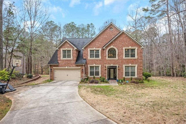 colonial inspired home featuring brick siding, a front yard, concrete driveway, and an attached garage
