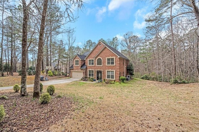 traditional-style home with a front yard, driveway, central AC, a garage, and brick siding
