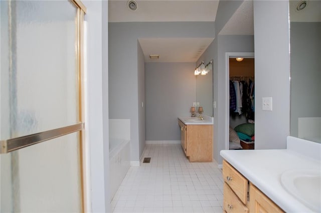 1775 Whooping Creek Rd, Carrollton, GA 30116 - full bathroom featuring tile patterned floors, two vanities, a garden tub, a shower stall, and a spacious closet