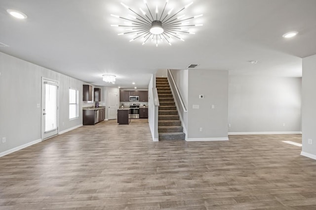 unfurnished living room with hardwood / wood-style floors and a chandelier